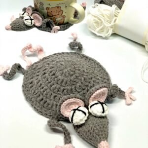 Gray crochet mouse coaster shown with a mug and yarn.