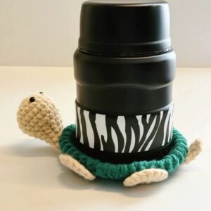Green crochet turtle coaster with a bottle placed on top.